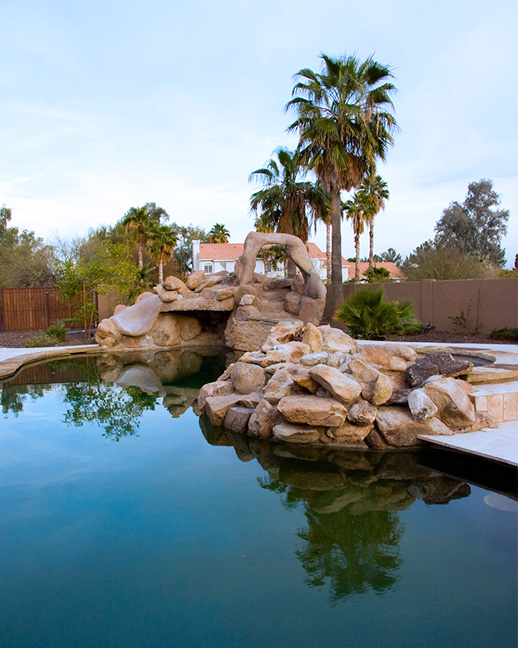 Crystal clear swimming pool with comfortable seating area and mature desert trees